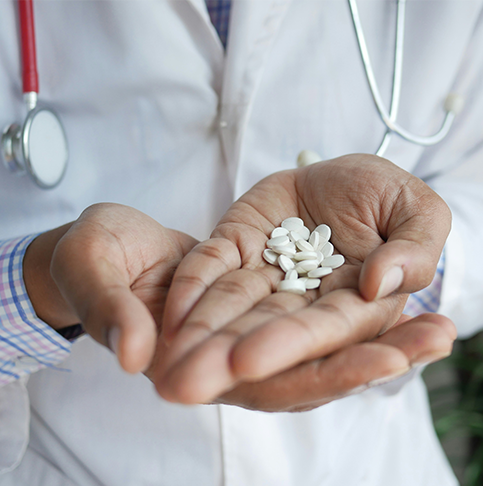 Arzt hält weiße Tabletten in geöffneten Händen